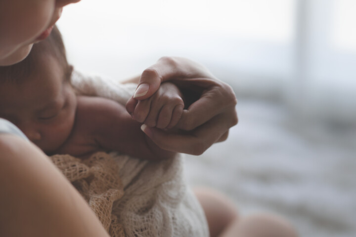 Close up of Mother holding hands of newborn baby and sunlight in the morning.