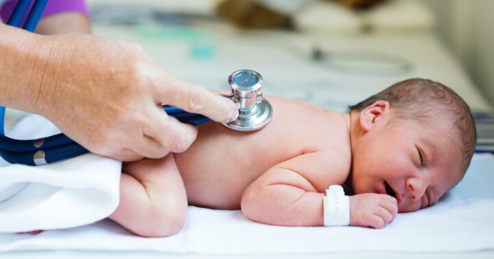 Baby lying on stomach and the doctor listening to heartbeat