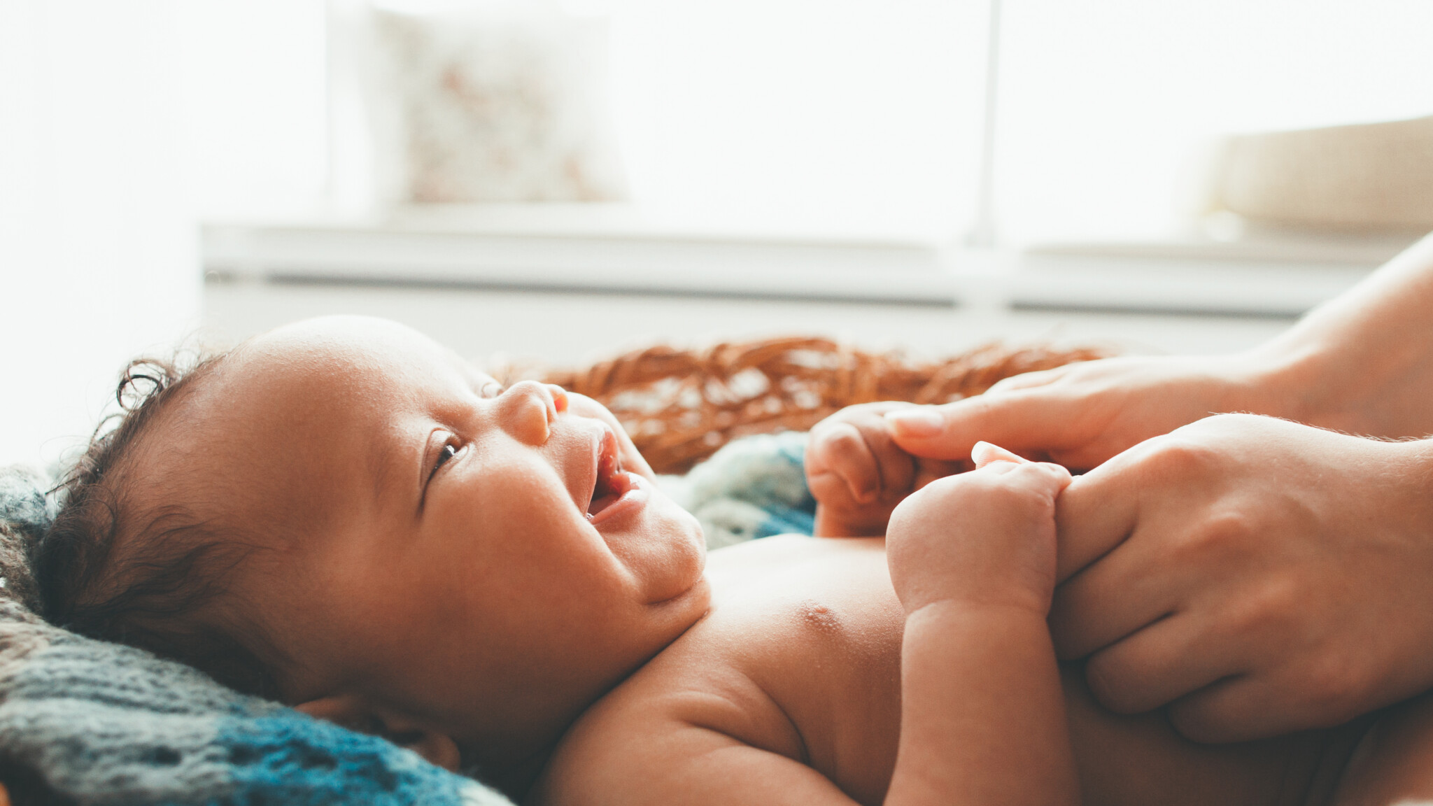 Newborn baby smiling at mother.