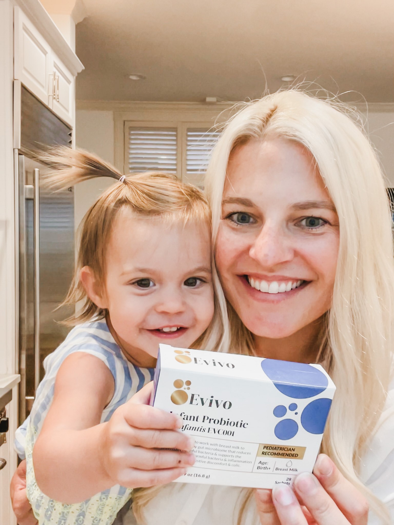 Mother and baby holding Evivo infant probiotic powder package.