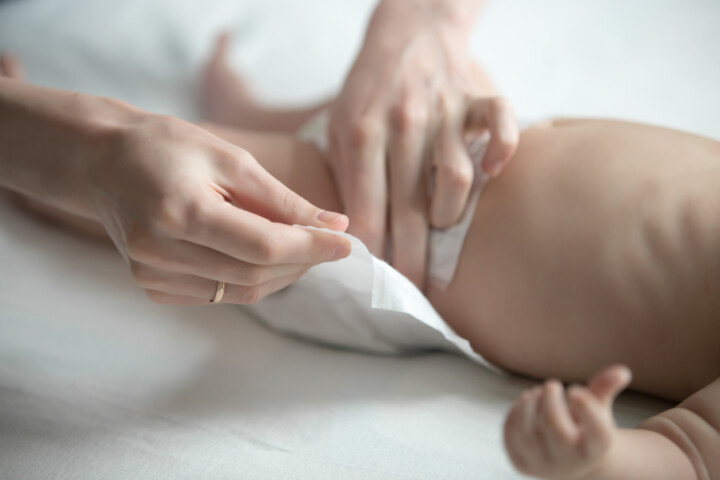 Female hands fixing a diaper on a newborn baby
